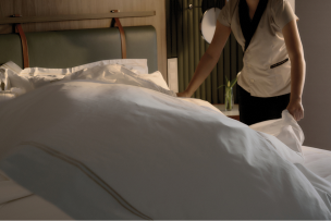 Bed being prepared with crisp Oceania linens