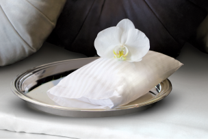 Folded linens with orchid on a silver tray